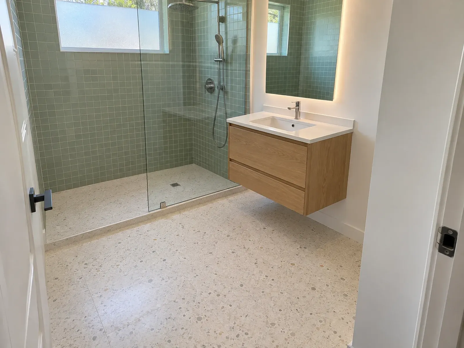 Bathroom remodeling in Los Angeles, CA: green tile walk-in shower with glass panel and floating oak vanity