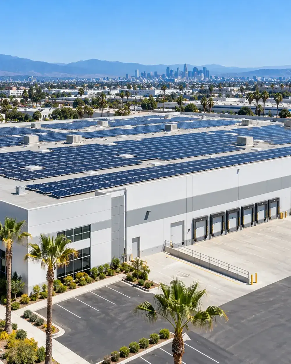 Commercial and industrial solar in Los Angeles, CA: rows of solar panels covering a warehouse roof with a loading dock and parking lot