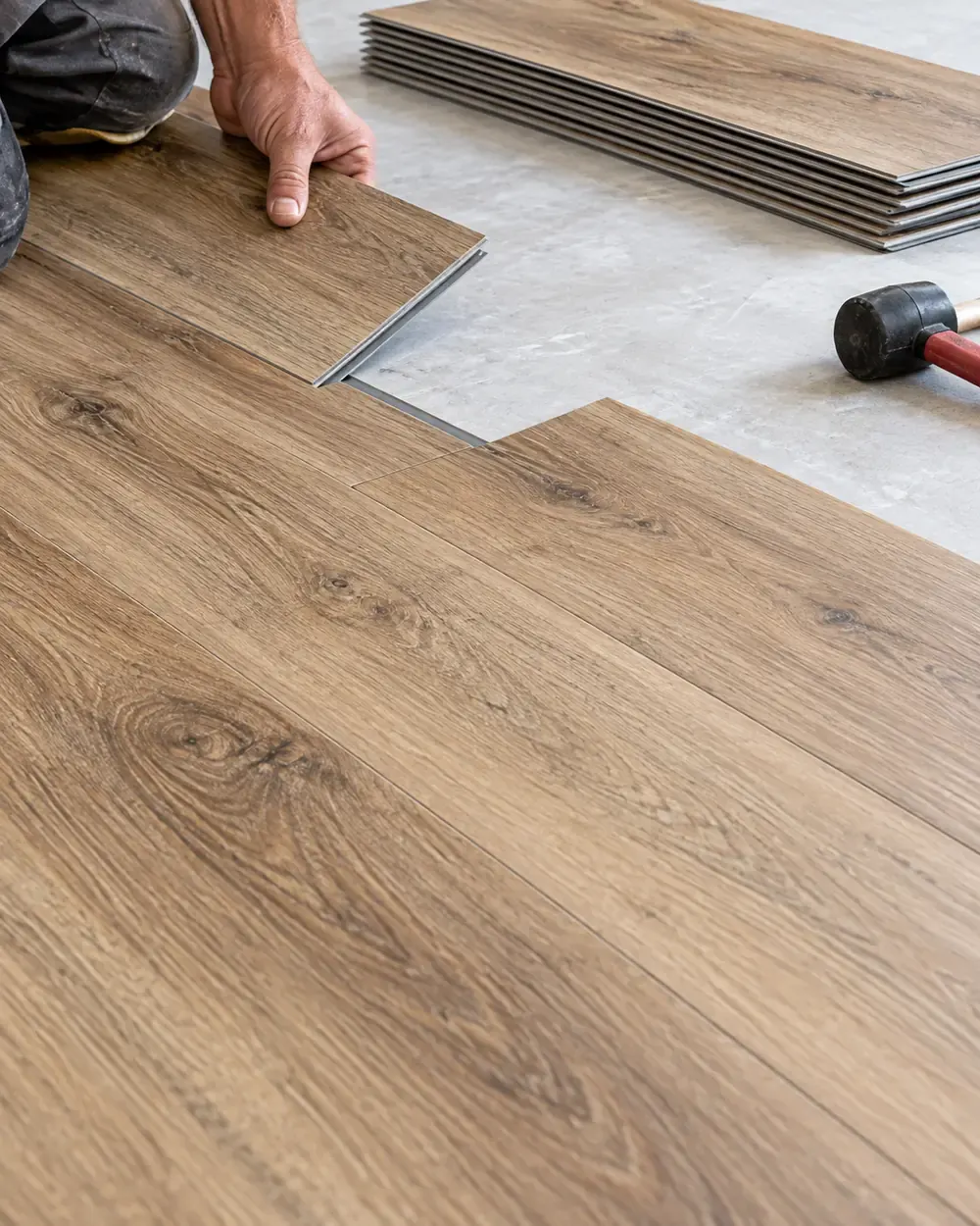 Luxury vinyl plank installation in Los Angeles: installer clicking a plank into place with a rubber mallet