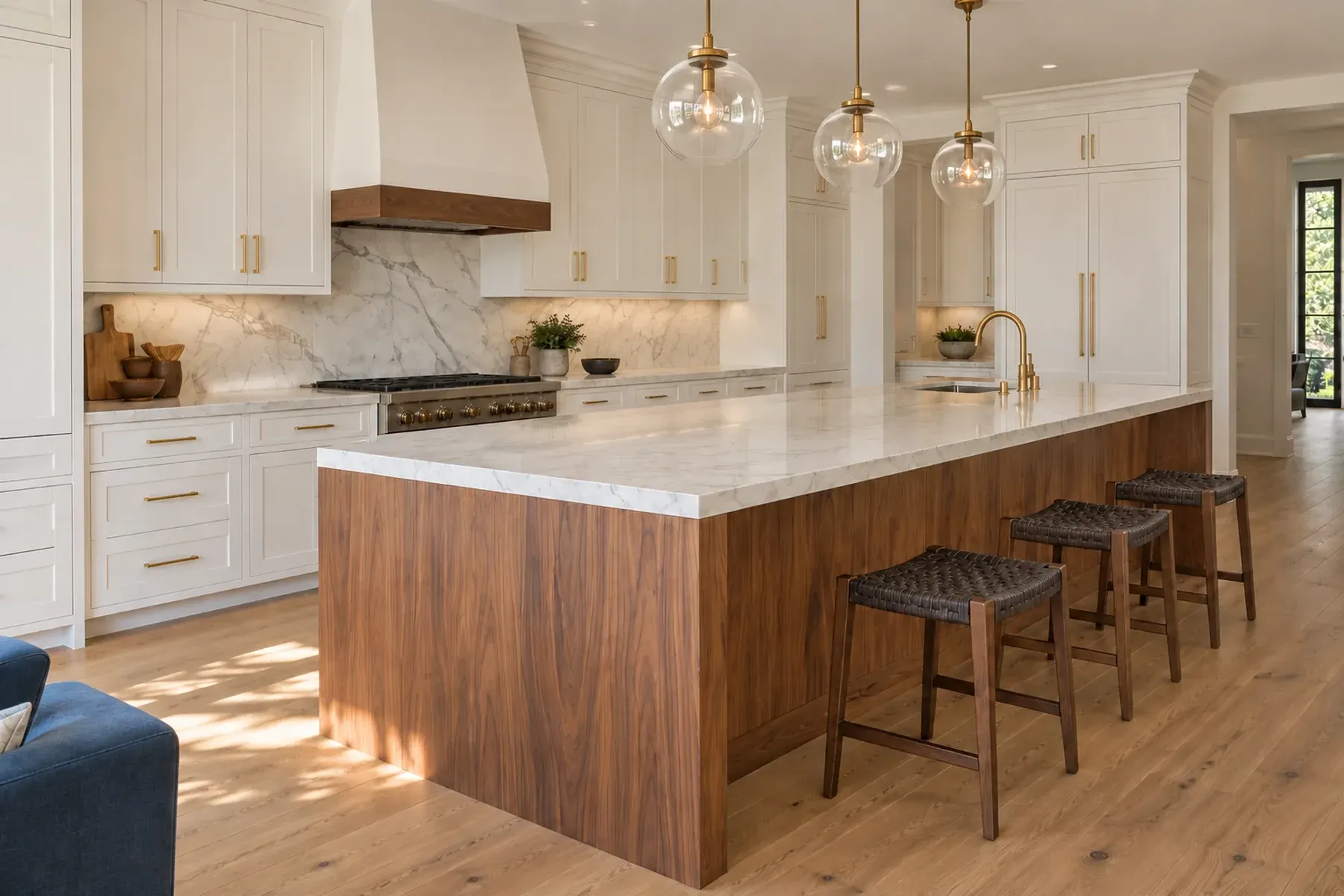 Modern kitchen remodel in Beverly Hills with long walnut island, marble waterfall top, white shaker cabinets and glass pendant lights