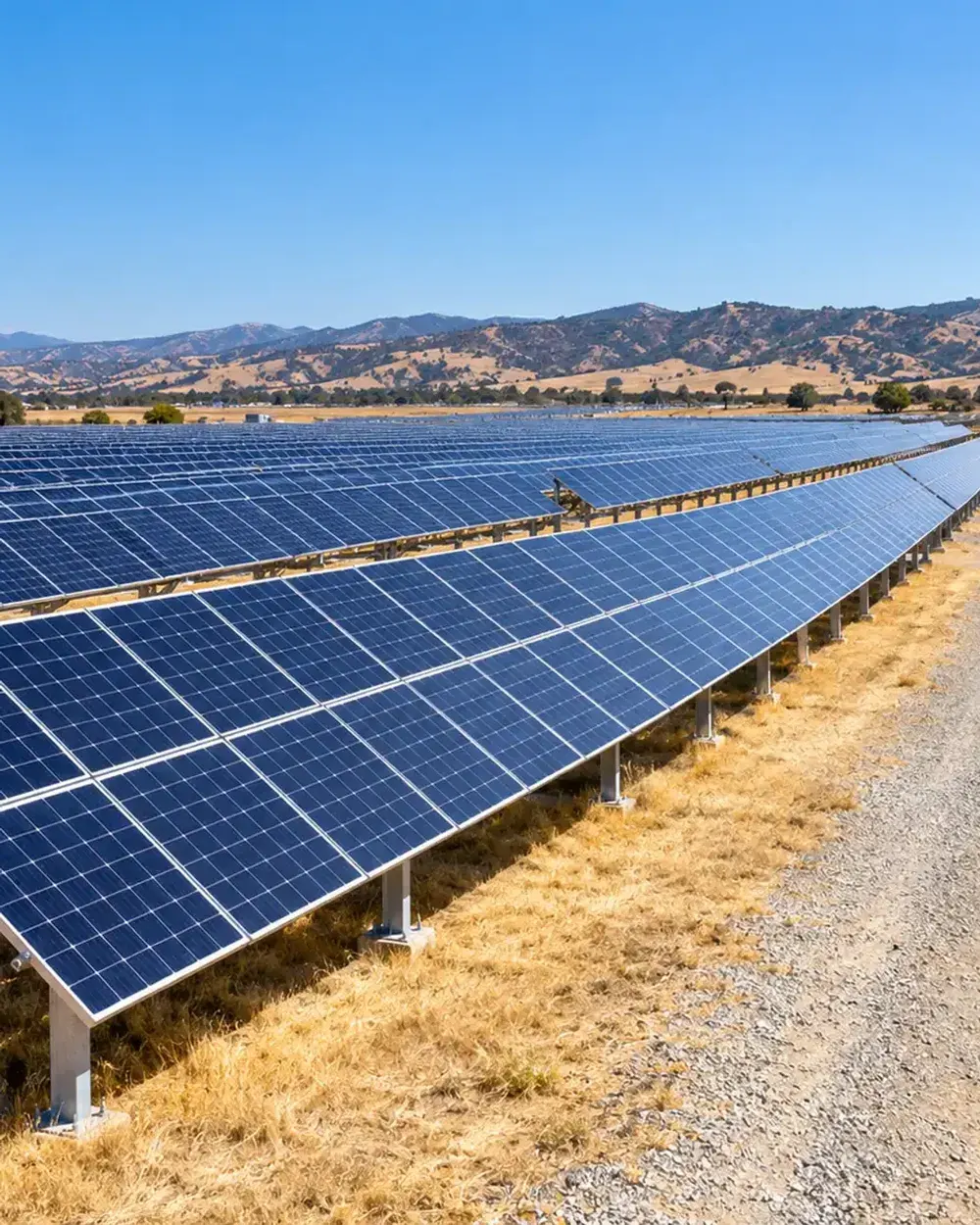 Ground-mounted solar power plant in Southern California: long rows of solar panels on steel racks with a gravel service road